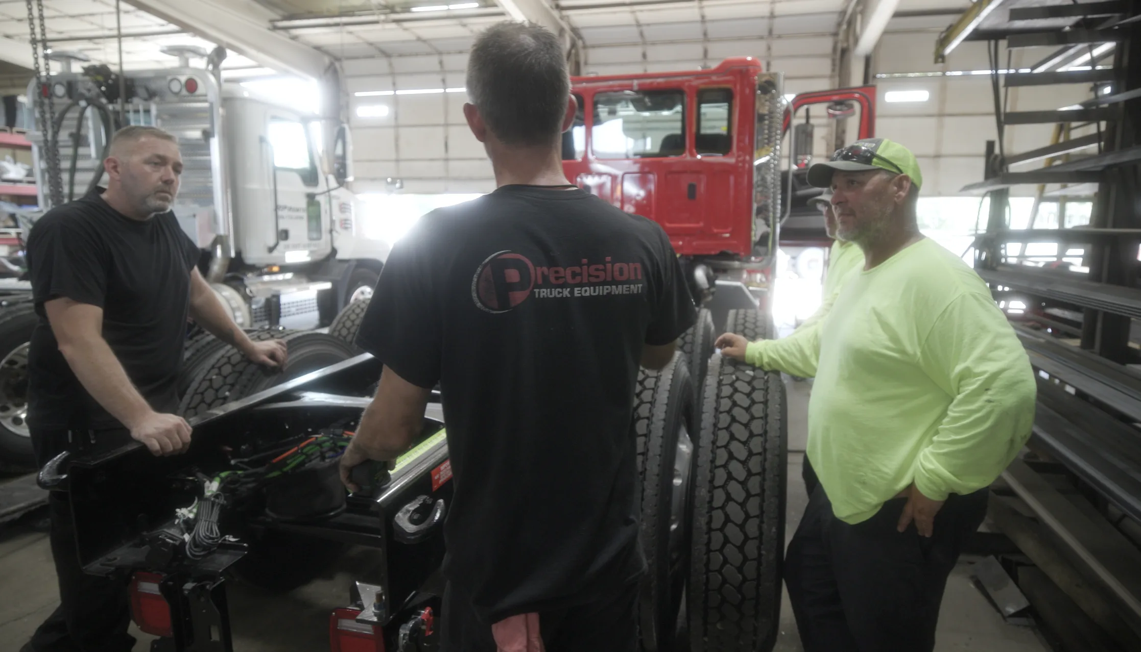Precision Truck Equipment team discussing work beside a truck chassis